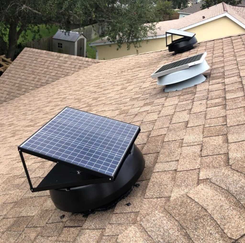 A solar attic fan mounted on a rooftop with brown shingles.