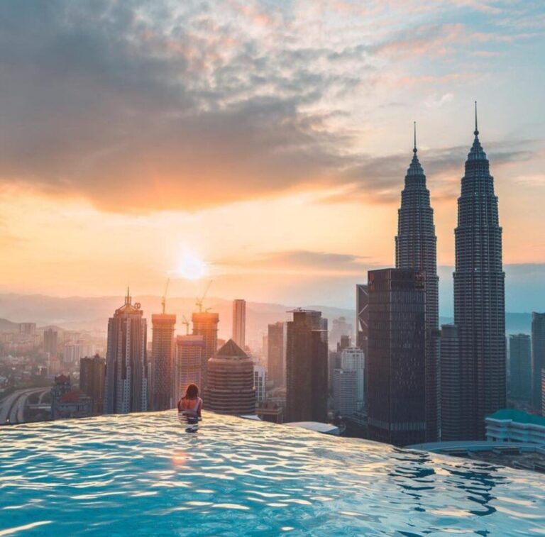 Person in an infinity pool overlooking a sky scrapers
