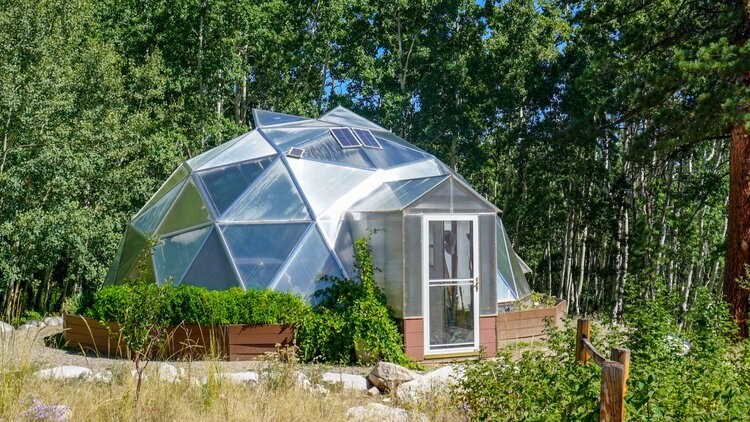 A domed greenhouse with a solar attic fan installed.