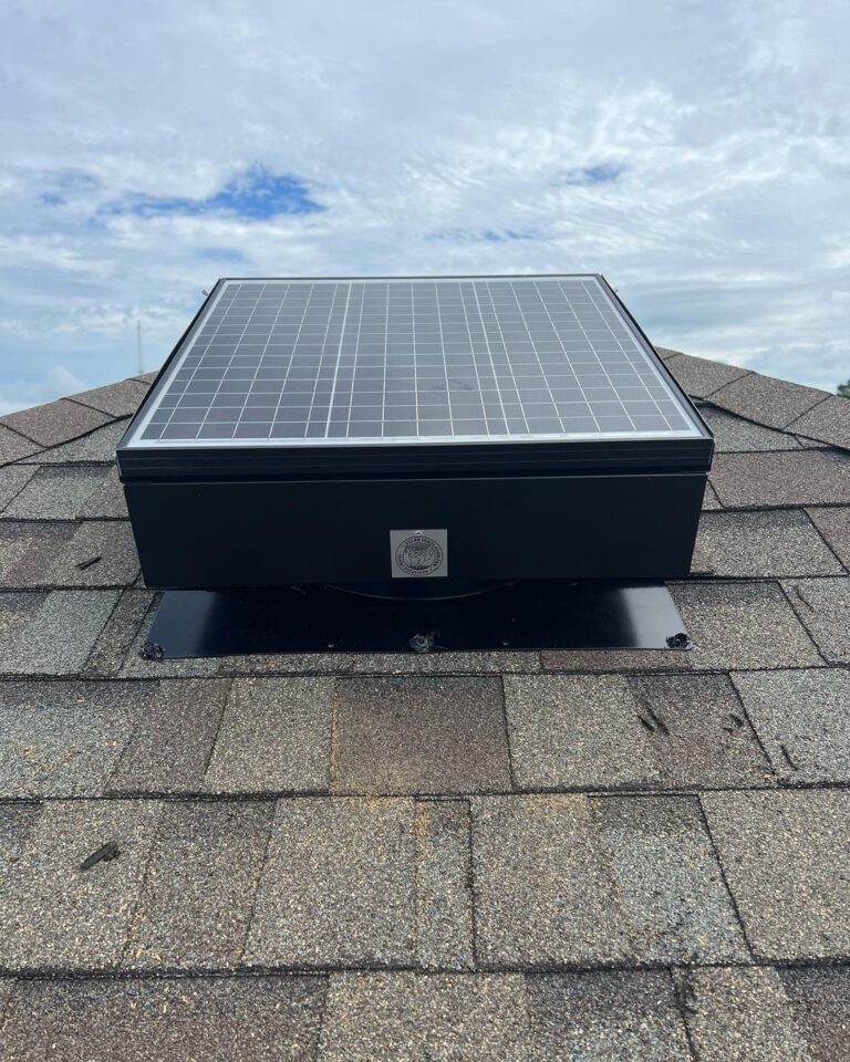 A solar attic fan on a roof with grey shingles